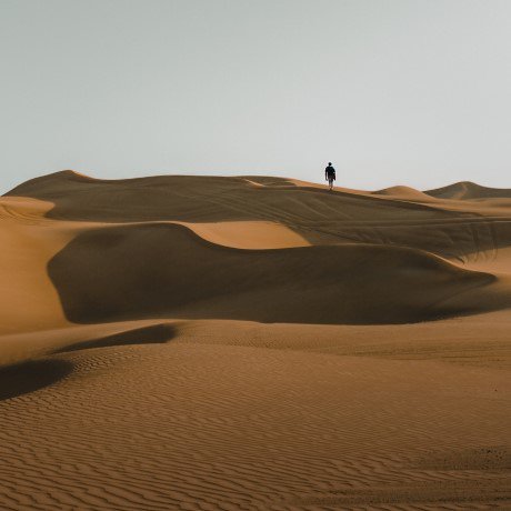 Silhouette of a person in the distance, walking in a desert. 
