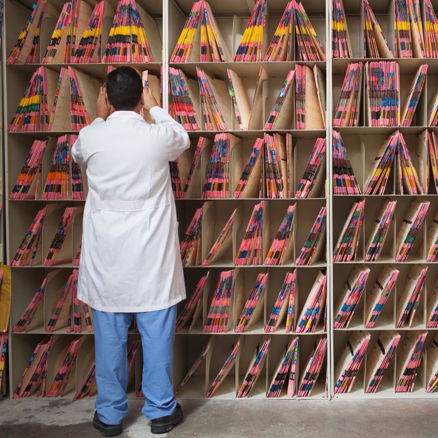medical professional sorting through shelves of patient files. 